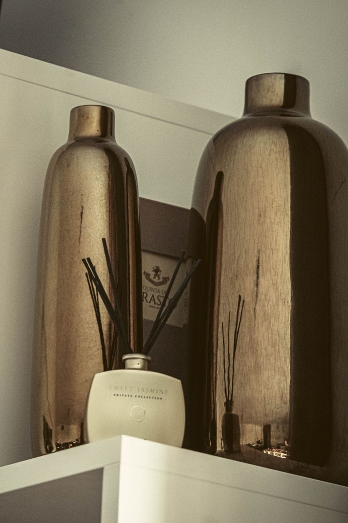 Sophisticated arrangement of metallic vases and sweet jasmine diffuser on a shelf.